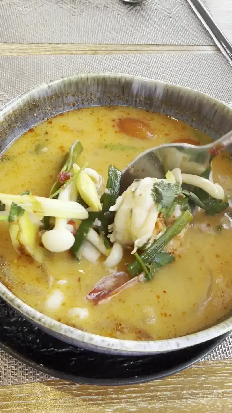 A bowl of seafood soup with mushrooms and fresh herbs