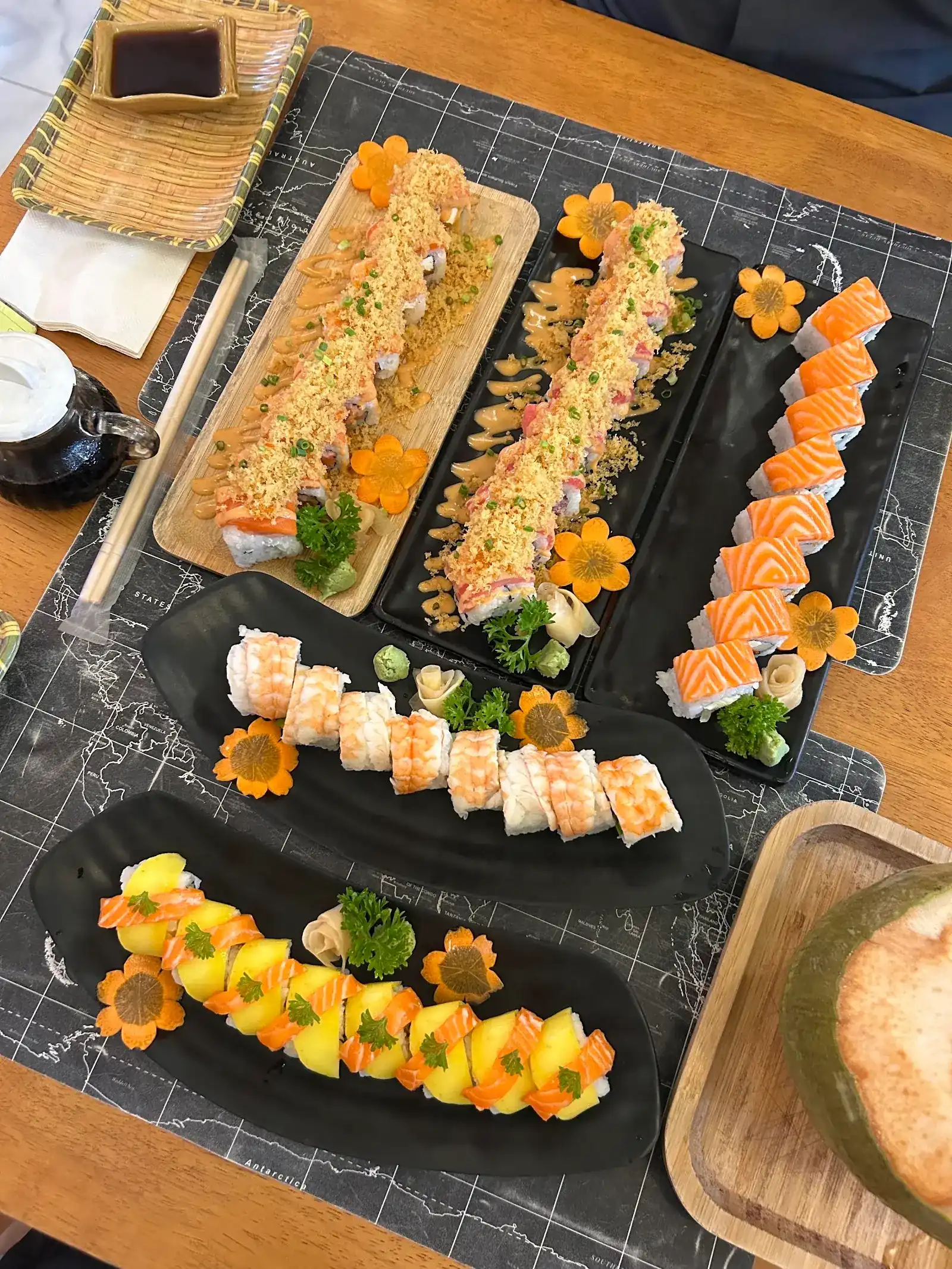 Four sushi rolls on long plates over a world-map placemat