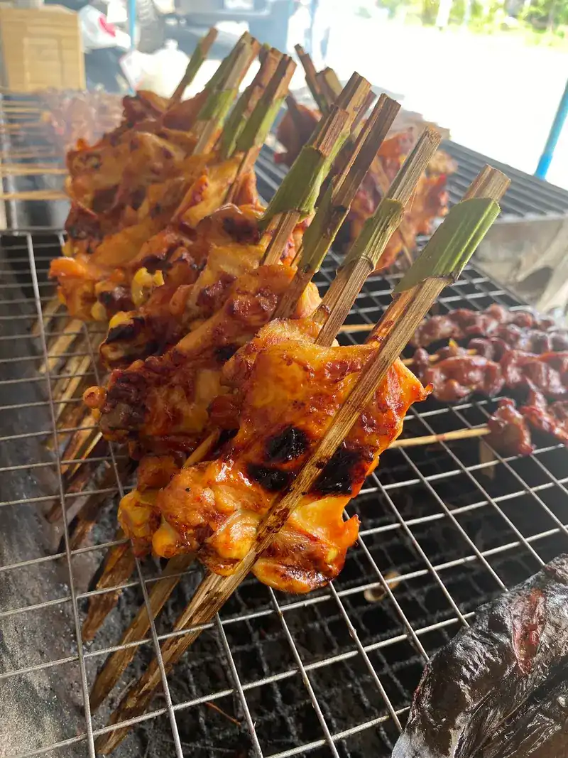 Chicken grilling on long bamboo skewers