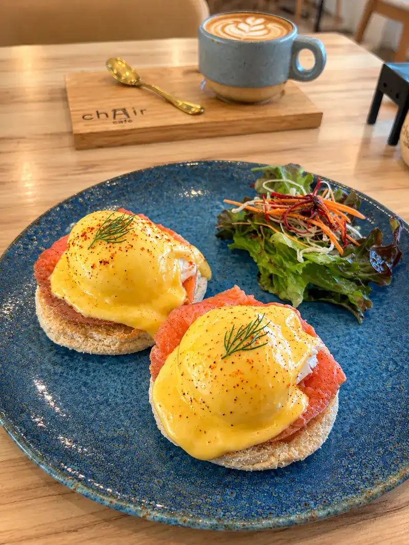 Poached eggs with salmon and hollandaise on muffins, with salad and a latte