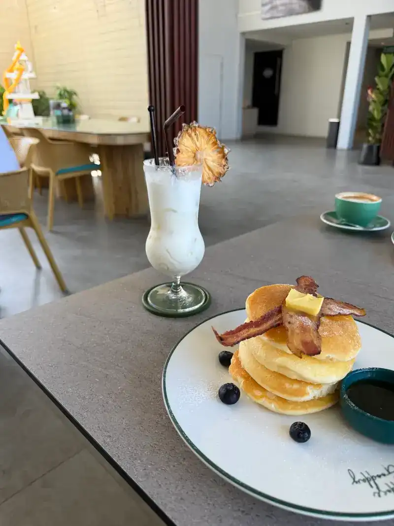 Pancakes with bacon, butter and blueberries, a coffee and a shake behind / แพนเค้กกับเบคอน เนย และบลูเบอร์รี มีกาแฟและเครื่องดื่มปั่นด้านหลัง