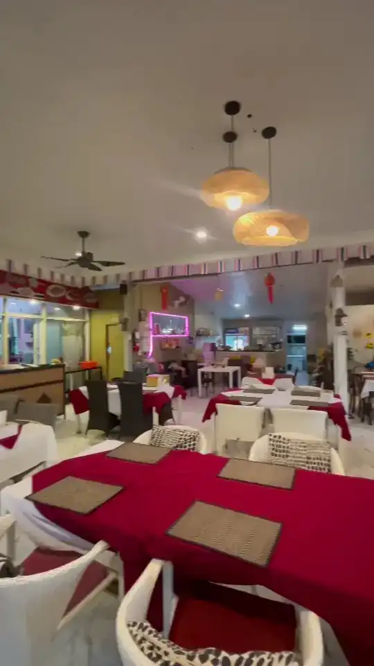 Tables in red cloths with woven placemats and white chairs under woven pendant lamps