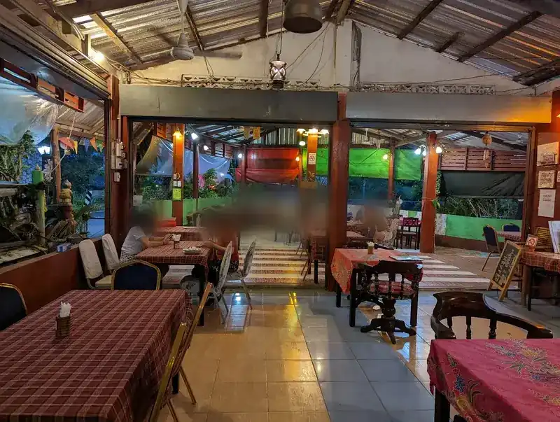 The open-sided dining room at dusk, with checked tablecloths and lanterns