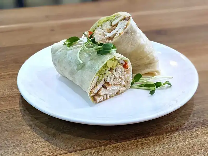 Chicken and salad wrap cut in half, with sprouts