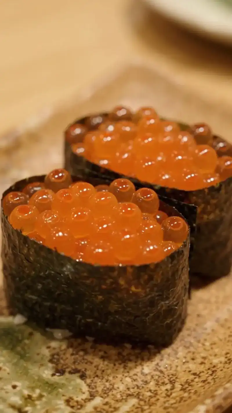 Two pieces of salmon roe sushi wrapped in nori