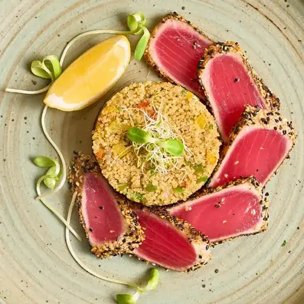 Slices of seared tuna around a mound of quinoa, with a wedge of lemon