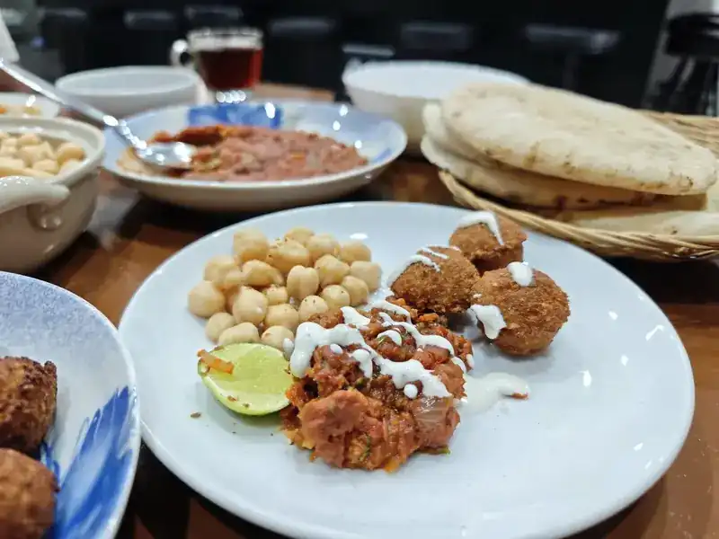 A plate of falafel and chickpeas with lime and a drizzle of sauce