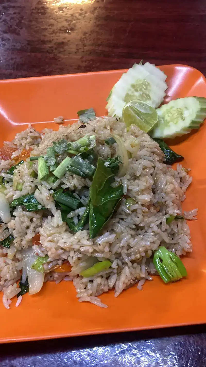 Fried rice with green vegetables, cucumber and lime on an orange plate