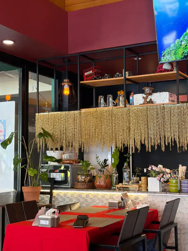 Inside: red-clothed tables by the counter, with plants and shelves
