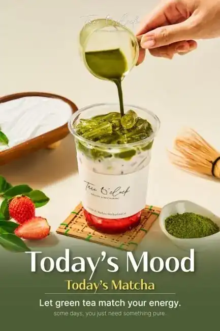 Iced matcha over strawberry and milk, with a bamboo whisk and a bowl of matcha powder