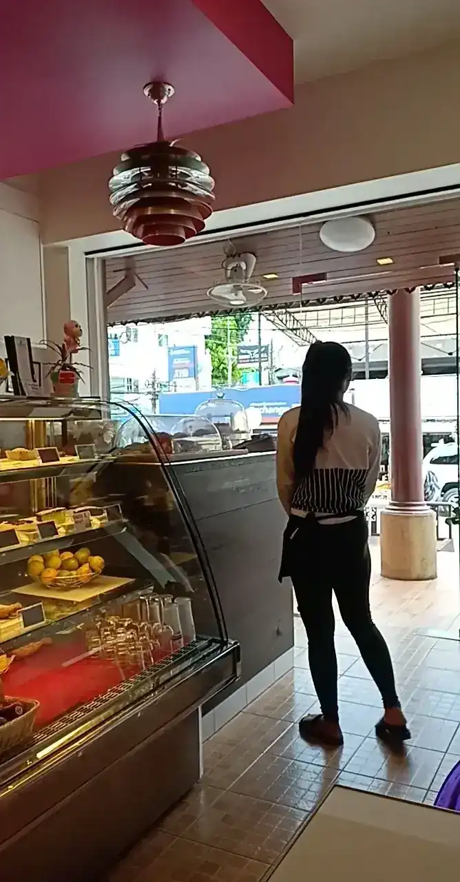 A staff member, seen from behind, waiting by the pastry counter near the open door