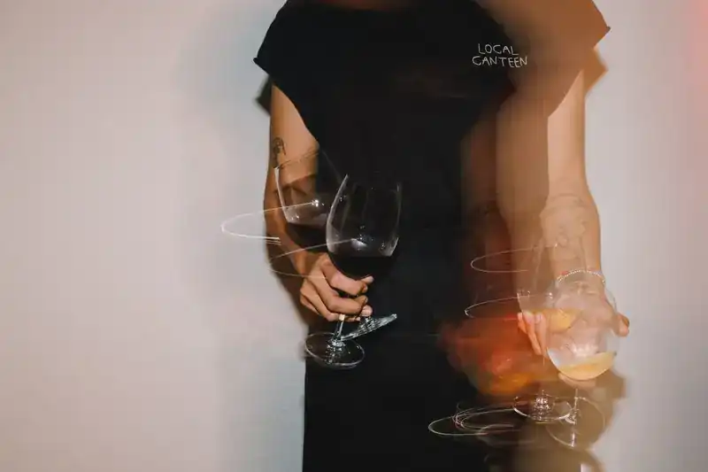 Hands carrying wine glasses, blurred in motion