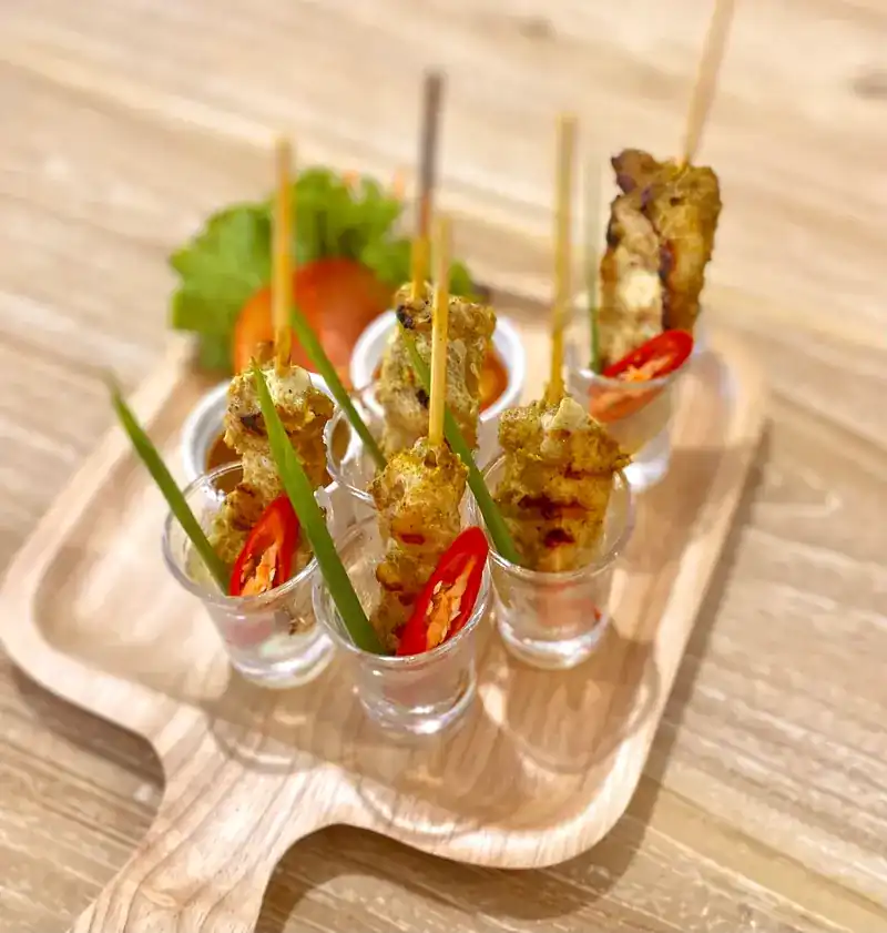 Grilled skewers served standing in small glasses with chilli and herbs
