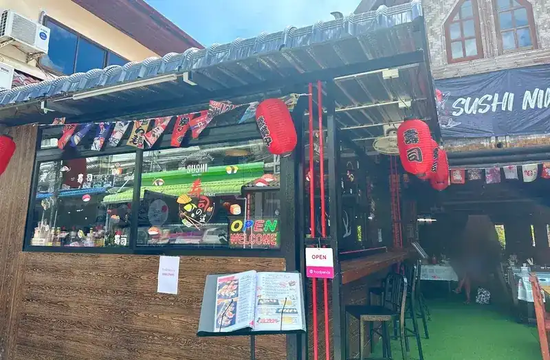 The shopfront on Karon Road: red lanterns, Japanese flags and the open dining room behind