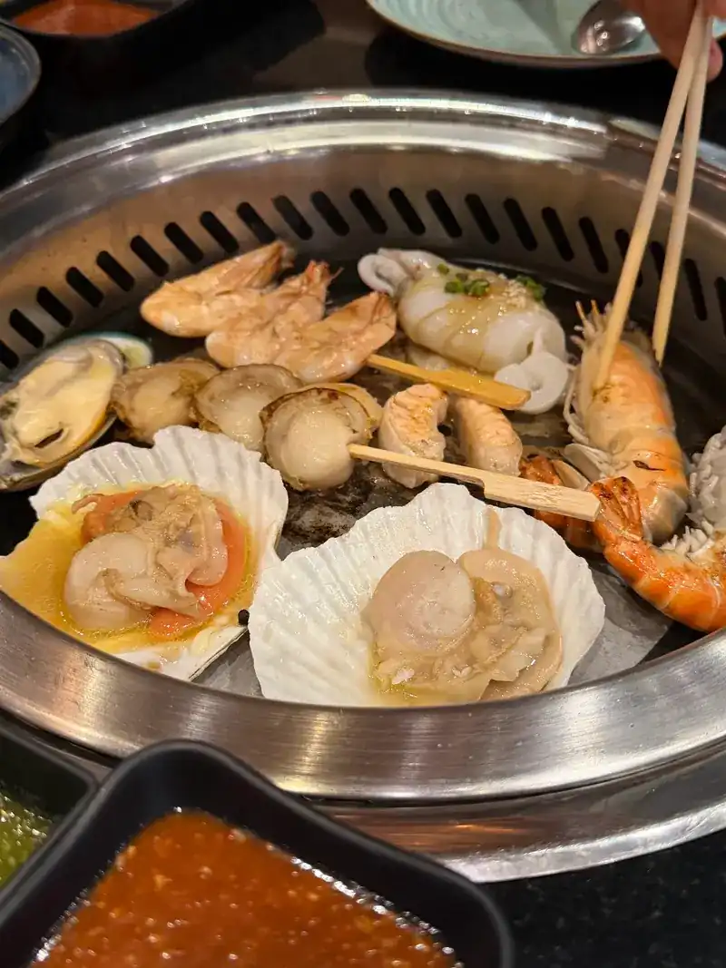 Scallops in their shells, prawns and mussels cooking on the grill
