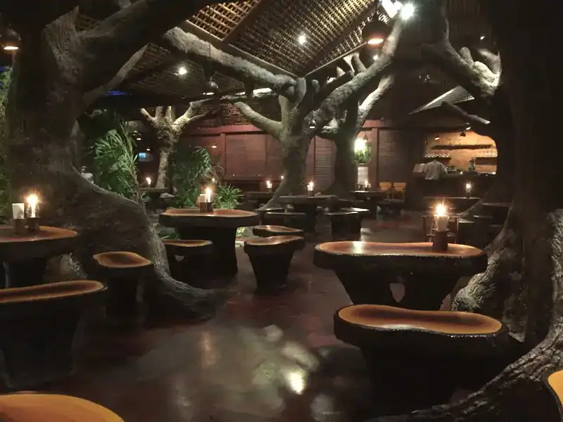 Candlelit stone tables between sculpted trees after dark / โต๊ะหินใต้ต้นไม้ปั้น จุดเทียนยามค่ำ