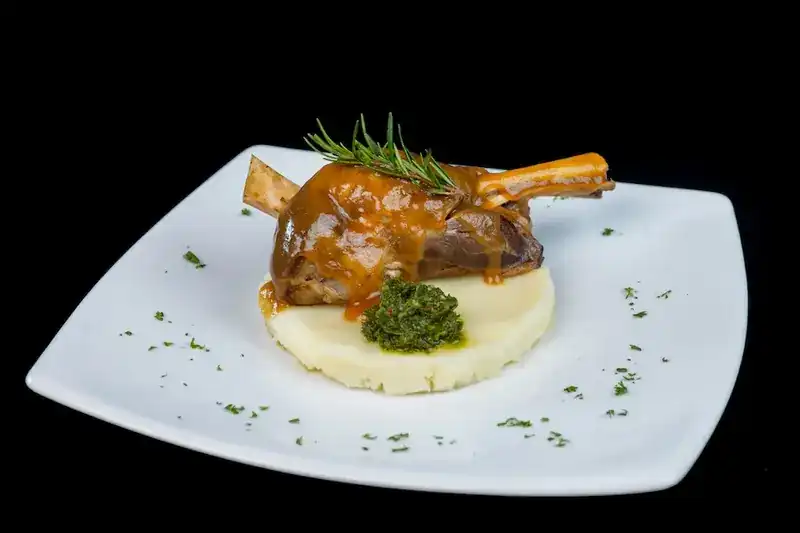 Braised lamb shank in gravy on mashed potato with a sprig of rosemary
