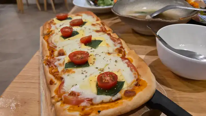 Long flatbread pizza with tomato, cheese and basil on a wooden board