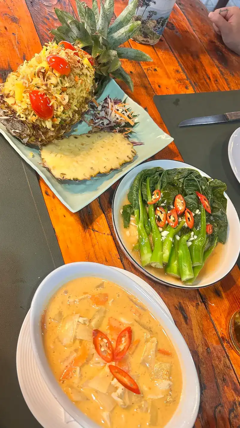 Pineapple fried rice, stir-fried kale with chilli and a bowl of curry on a wooden table | ข้าวผัดสับปะรด ผัดคะน้าใส่พริก และแกงหนึ่งถ้วยบนโต๊ะไม้