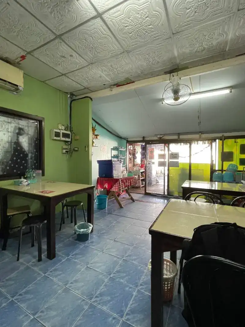 Inside Krua Kun Nok: green walls, blue floor tiles, a wall fan and tiled tables