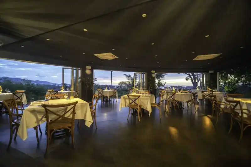 The dining room at dusk, its windows open to the hills and the sea