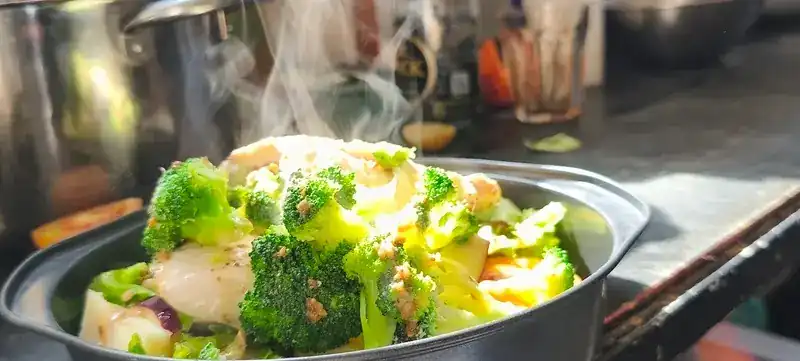 Steam rising from a pan of broccoli and vegetables