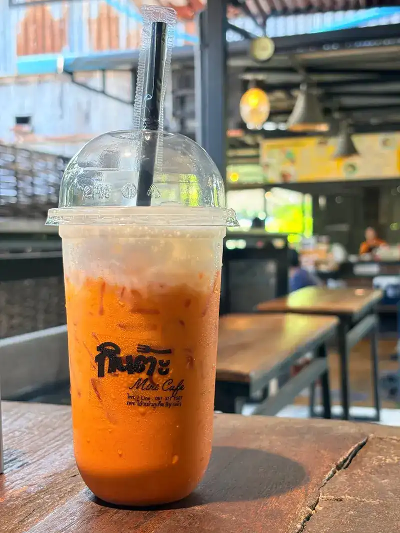 Iced Thai tea in a cup printed with the Kinta Mini Cafe name