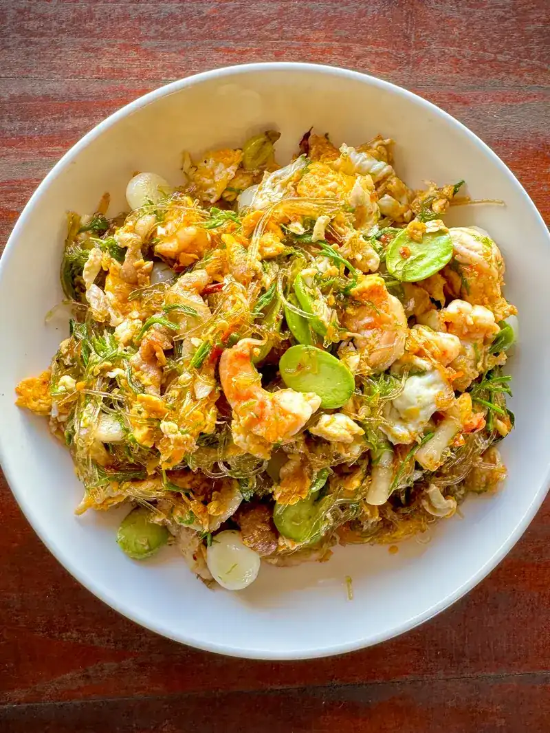 Prawns, egg and sator beans stir-fried with glass noodles in a white bowl