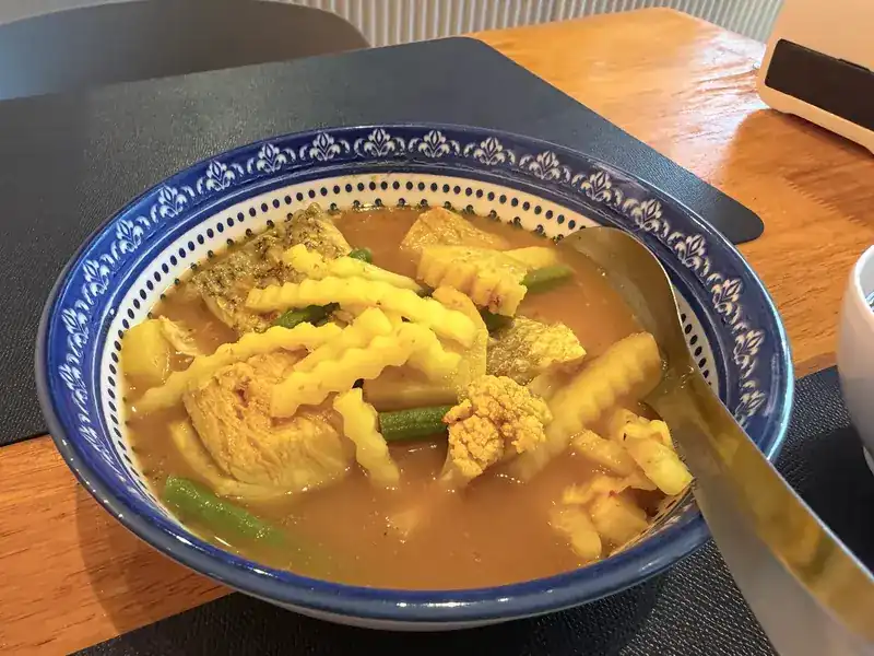 Fish curry with baby corn, long beans and cauliflower in a blue and white bowl