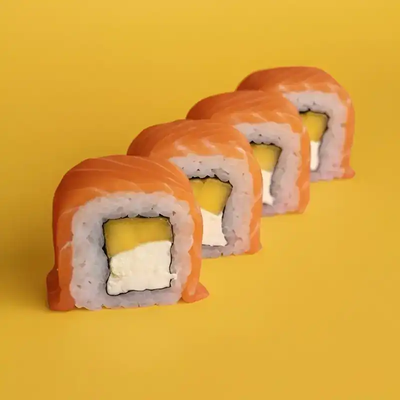 Salmon roll with mango and cream cheese on a yellow background