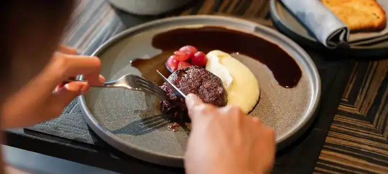 A Wagyu tenderloin with creamy mash and red wine jus being cut at the table