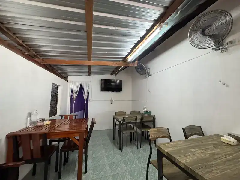 The dining room: wooden tables, wall fans and a pale tiled floor