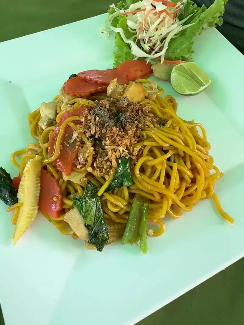 Yellow noodles stir-fried with vegetables, with a wedge of lime