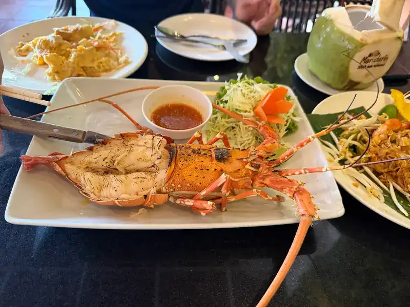 A whole lobster split and grilled, with dipping sauce and salad