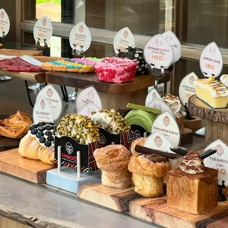Croissants, cakes and pastries on wooden boards at the counter