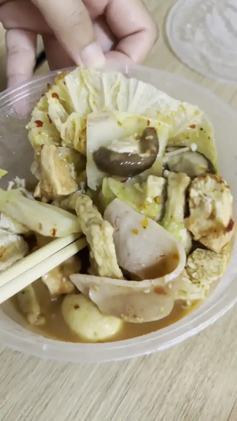 Cooked pieces in mala broth with Chinese cabbage and mushroom, chopsticks in hand