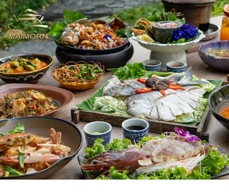 A table of Maimorn dishes: sliced pomfret for the hot pot, fried sea bass, crab, prawns and curries