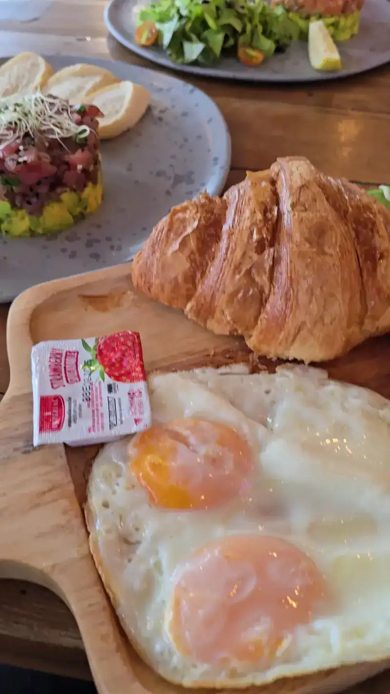 Croissant and two fried eggs on a wooden board / ครัวซองต์กับไข่ดาวสองฟองบนเขียงไม้