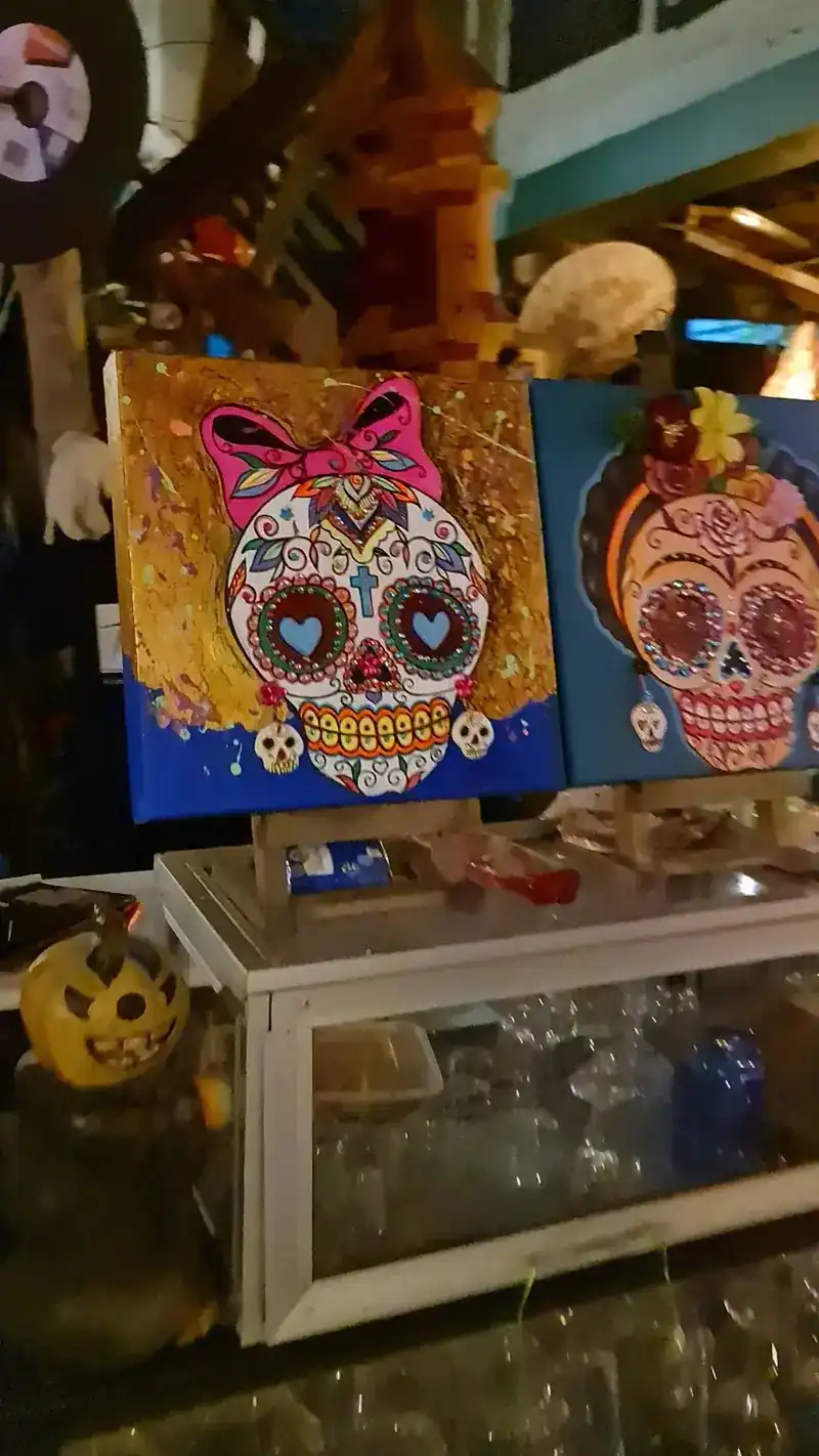 Two bright paintings of skulls decorated with flowers and bows
