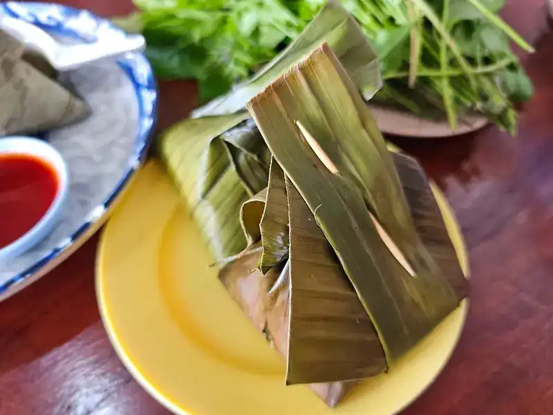 A wrapped ba chang pinned with a toothpick on a yellow plate