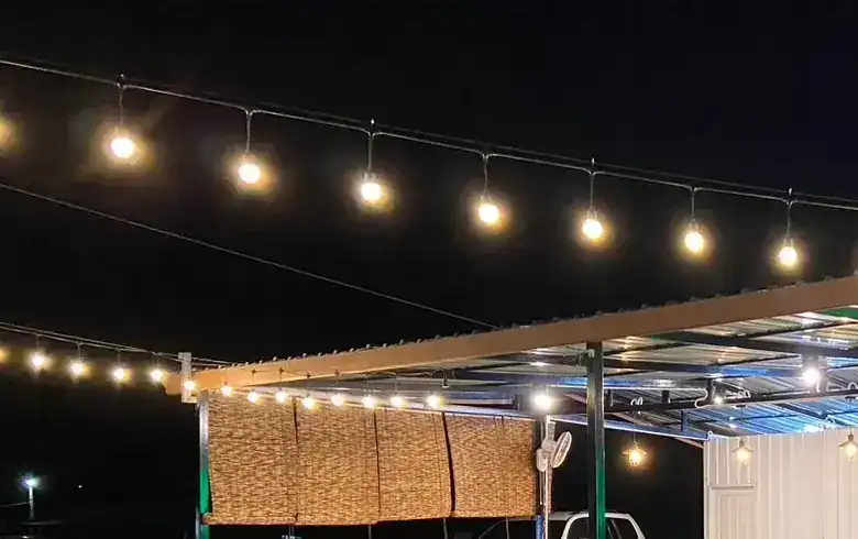 String lights against the night sky over the terrace roof and its bamboo blinds.
