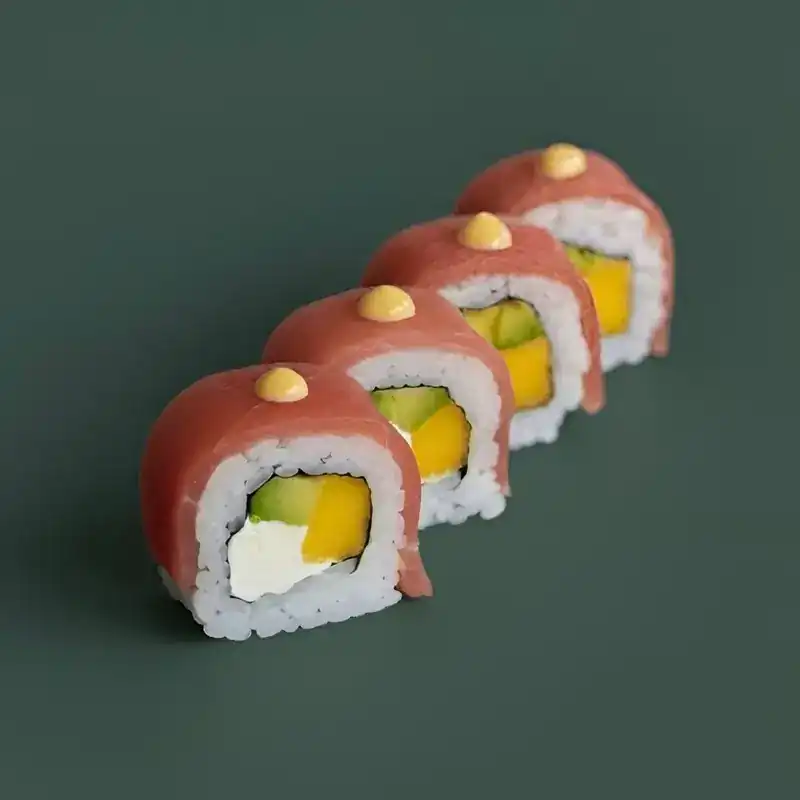 Tuna roll with mango, avocado and cream cheese on a dark green background
