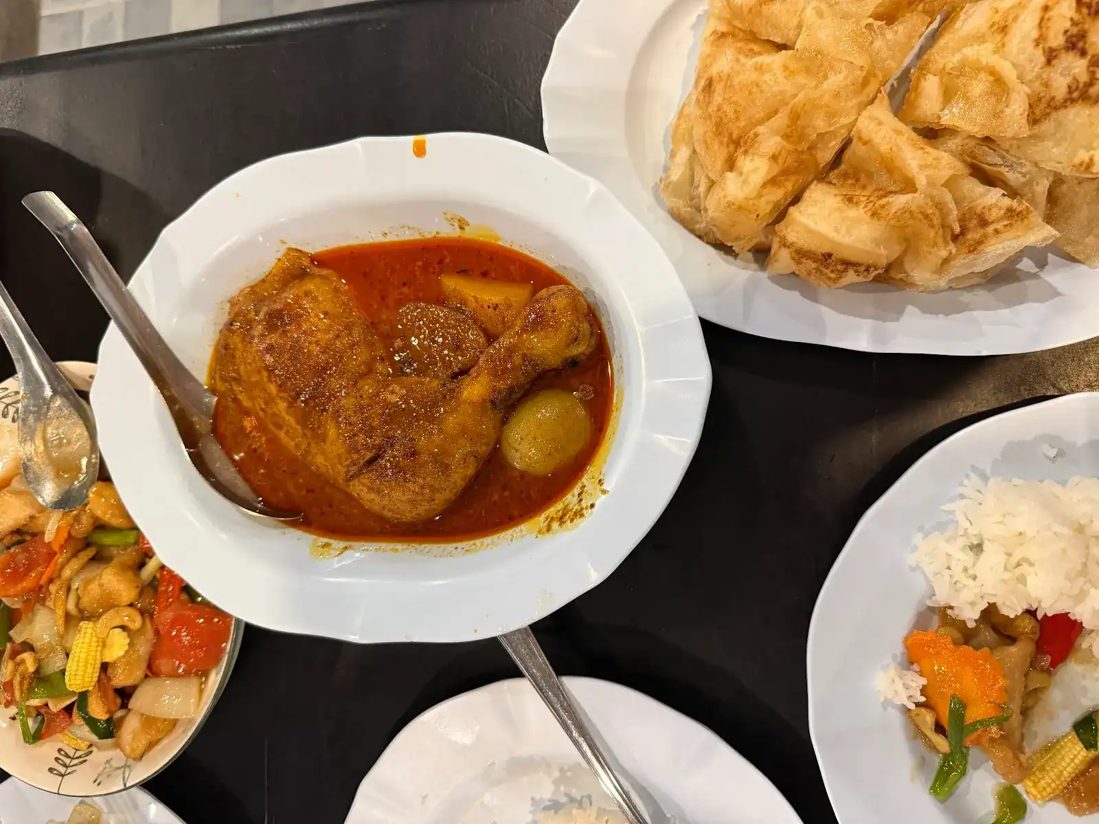 Chicken curry with potato in a white bowl, with roti and rice beside it / แกงไก่ใส่มันฝรั่งในชามสีขาว วางคู่กับโรตีและข้าว