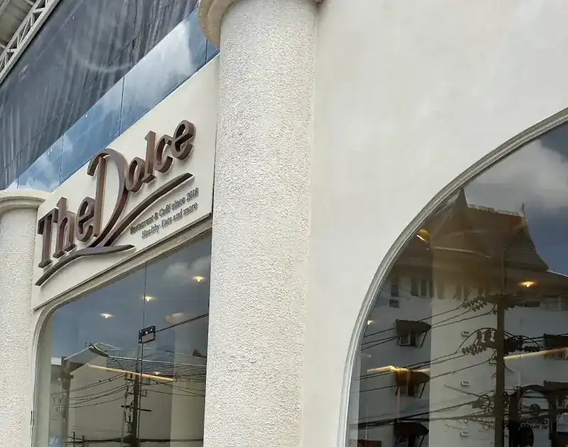 The cream front of TheDolce on Phangmuang Sai Kor, with its brown lettering and oval windows