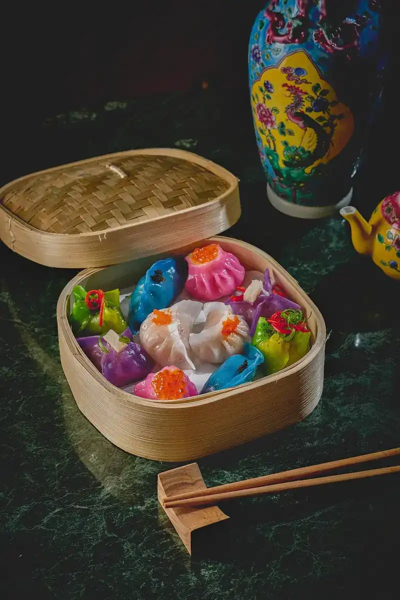 Colourful dumplings in a bamboo steamer on green marble