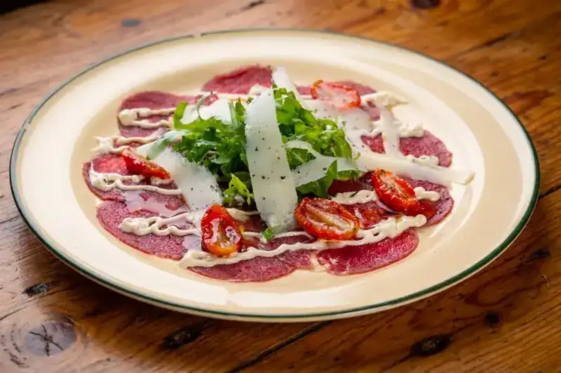 Beef carpaccio with rocket, parmesan shavings and tomatoes