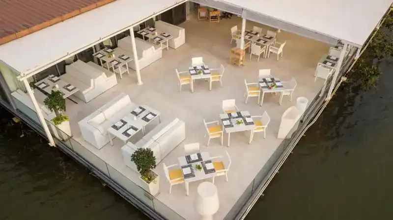 The open terrace from the air: white sofas and tables on a deck over the water
