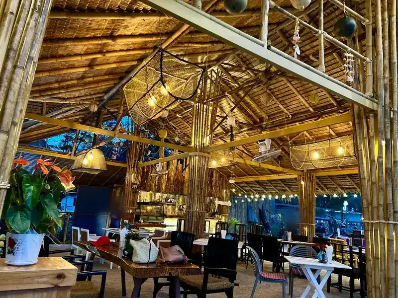 Inside the bamboo hall: woven lamps and fishing floats hang from the thatched roof over wooden tables