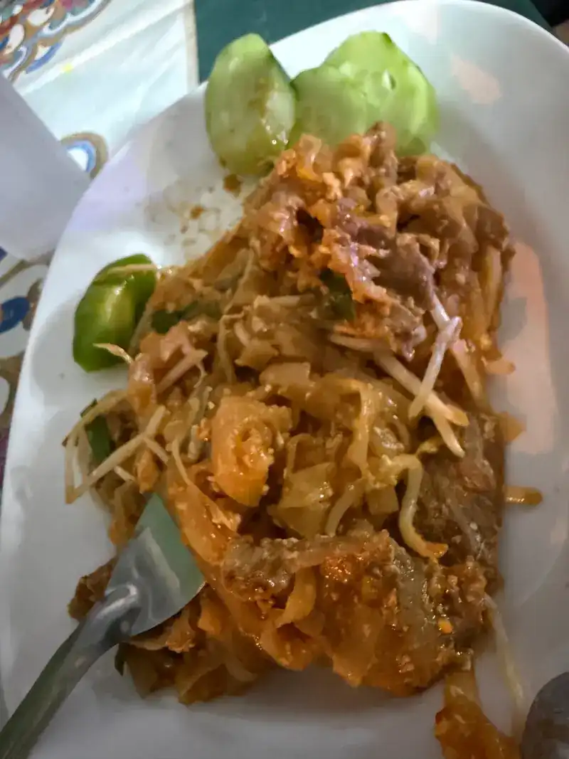 Wide rice noodles stir-fried in a red-brown sauce with bean sprouts, cucumber and lime on the side