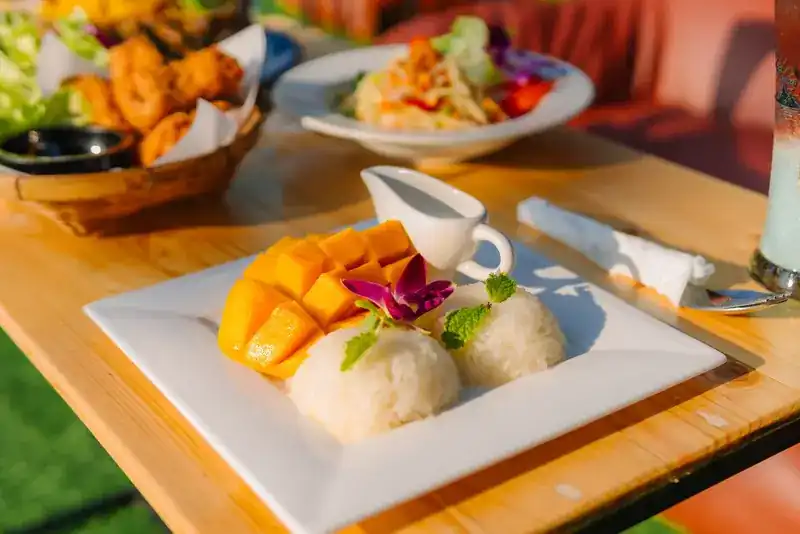 Mango with sticky rice, with fried snacks and a salad behind